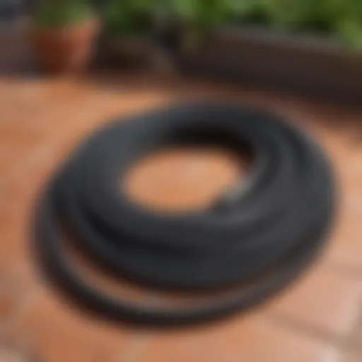 A black garden hose coiled neatly on a patio